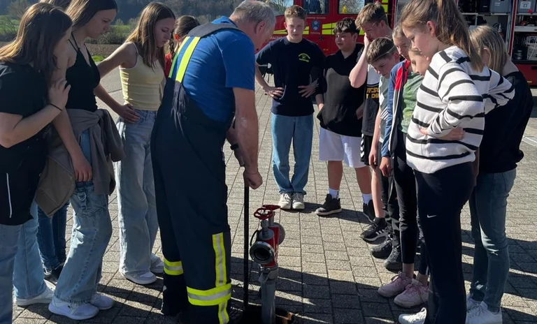 Interessiert schauen die Firmlinge zu, wie ein Hydrant in Betrieb genommen wird.jpg